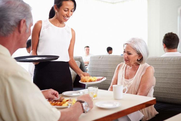 服务员在酒店餐厅为老年夫妇服务早餐